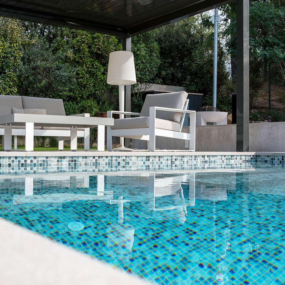 Mixed glass mosaic tile in a swimming pool with outdoor furniture on the patio deck