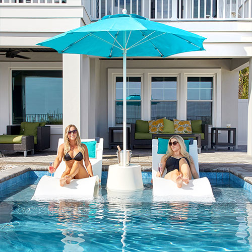 In-pool chaise lounge chairs and side table with umbrella on pool ledge