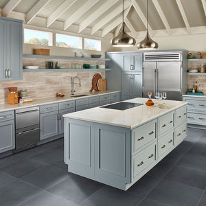 Large format gray porcelain tile on kitchen floor with beige stone tile backsplash