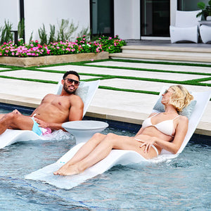 Swimming pool ledge with in-pool chaise lounge chairs and side table