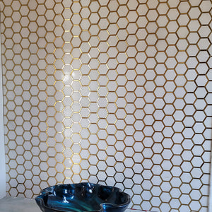 Metallic gold grout with white hexagon glass tile on bathroom wall