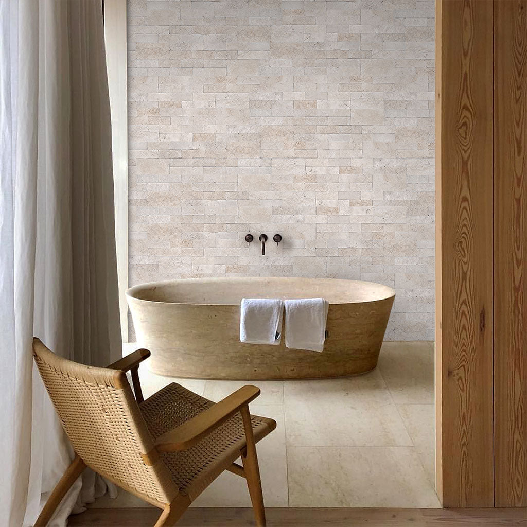 Beige natural stone ledger tile on bathroom wall with large soaking tub