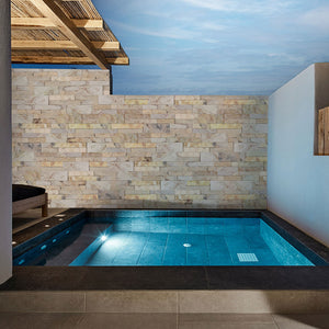 Beige natural stone tile on indoor pool accent wall