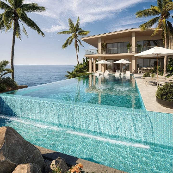 Luxury villa with an infinity pool overlooking the ocean, surrounded by palm trees.