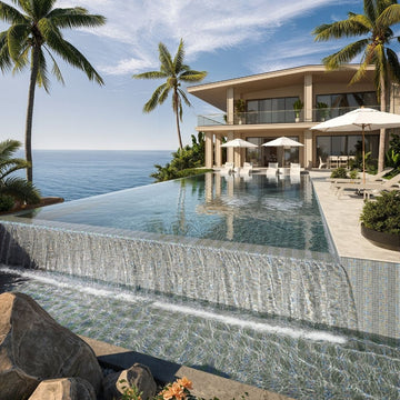 Luxury villa with an infinity pool overlooking the ocean, surrounded by palm trees.
