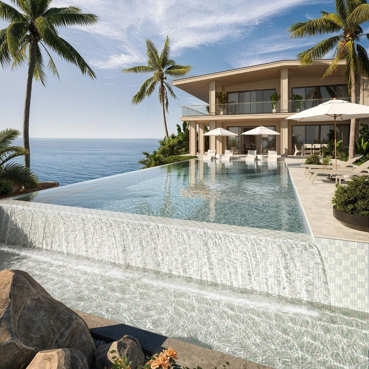 Luxury villa with an infinity pool overlooking the ocean and palm trees.