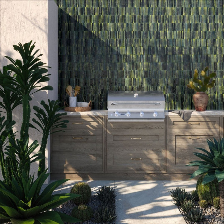 Outdoor kitchen with grill and cabinets against a green tiled wall