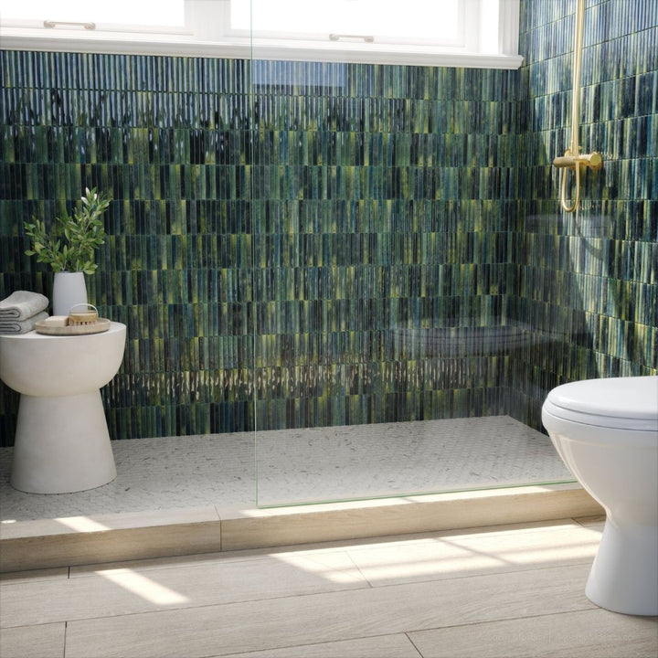 Modern bathroom with green mosaic tiles, white toilet, and shower area.