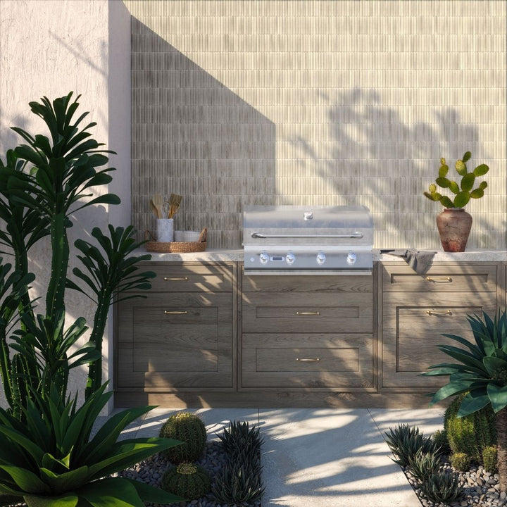 Outdoor kitchen with a grill and cabinets, surrounded by plants.