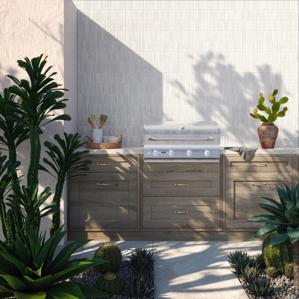 Outdoor kitchen with wooden cabinets and a grill, surrounded by plants.