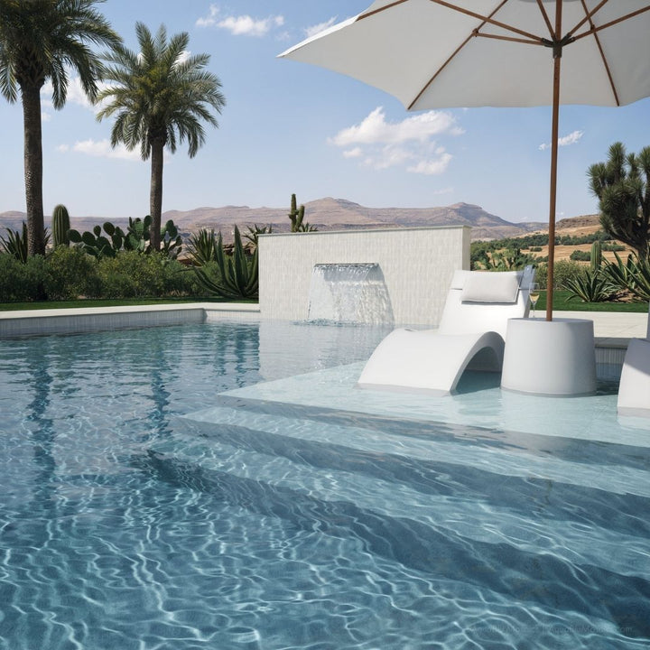 Pool area with lounge chairs, umbrella, and scenic background
