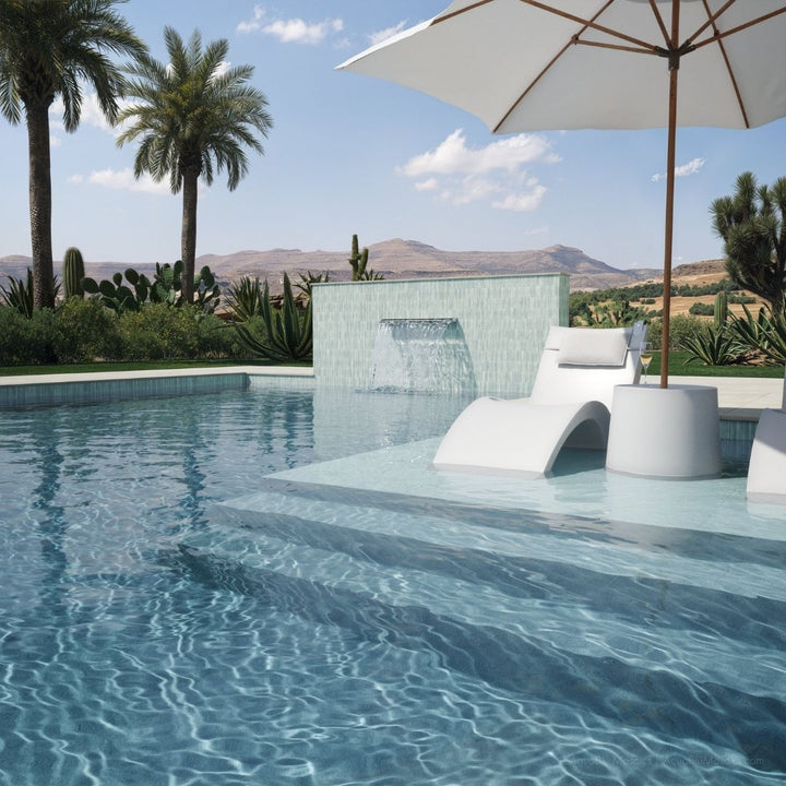 Pool area with lounge chairs, umbrella, and scenic background