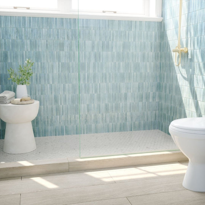 Bathroom with light blue tiled walls and a white toilet.
