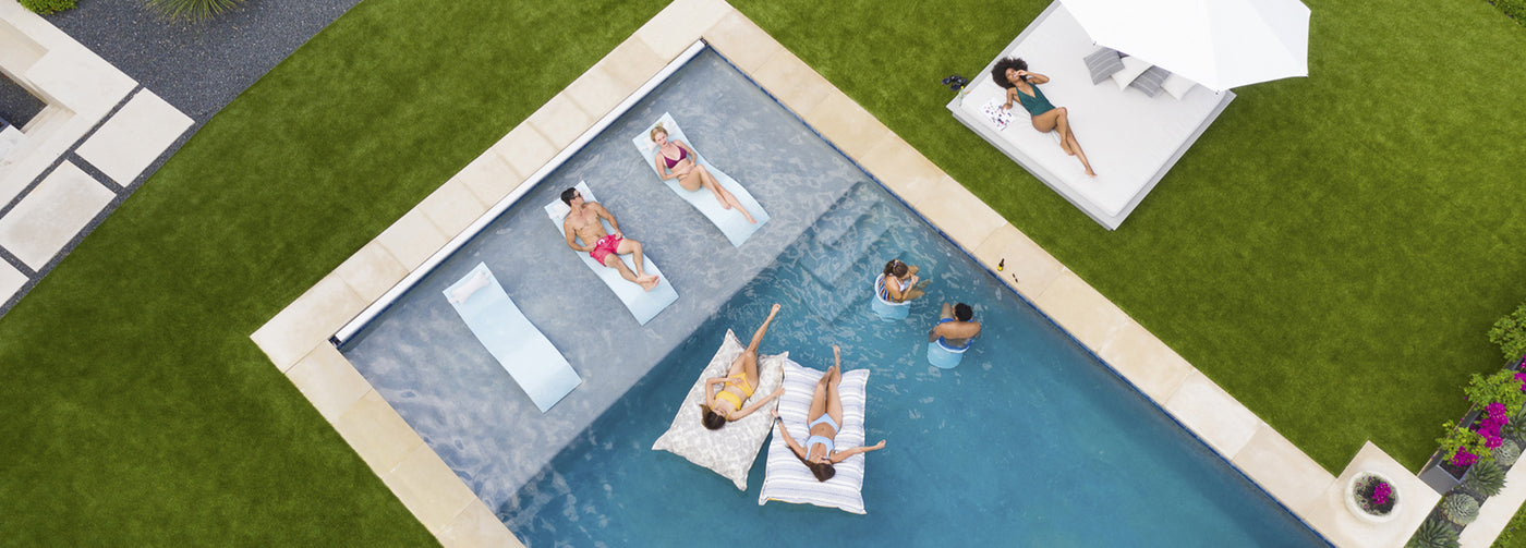 Aerial view of a pool with people lounging on pool floats, in-pool loungers, and in-pool bar stools