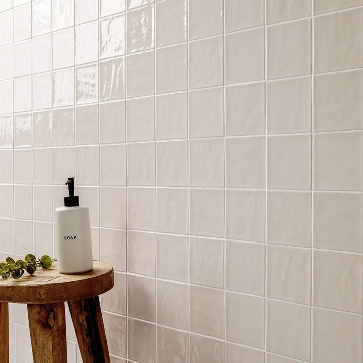 Terranello Dune 4" x 4" Glossy Bathroom Backsplash Tile with a stool, plant and soap.