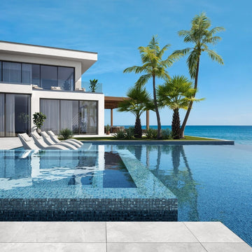 blue mosaic glass tile in swimming pool with chairs and palm trees