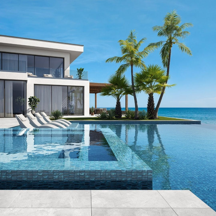 blue mosaic glass tile in swimming pool with chairs and palm trees