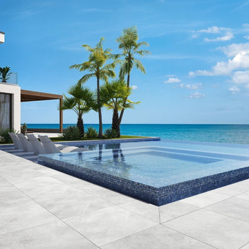 blue mosaic glass tile in swimming pool with chairs and palm trees