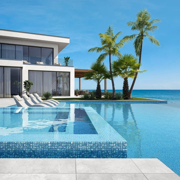 blue mosaic glass tile in swimming pool with chairs and palm trees