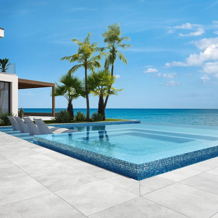 blue mosaic glass tile in swimming pool with chairs and palm trees