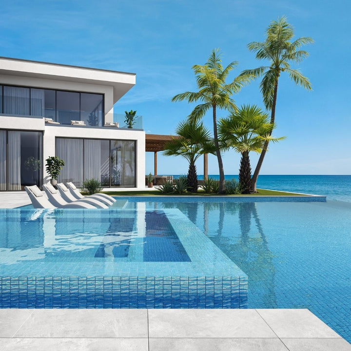 blue mosaic glass tile in swimming pool with chairs and palm trees