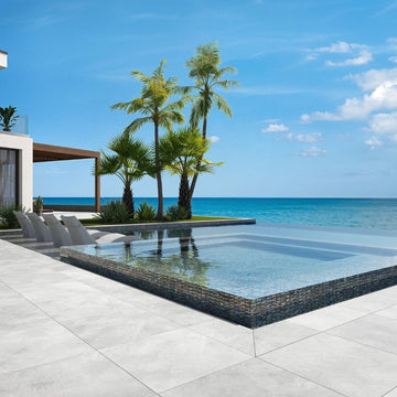 grey mosaic glass tile in swimming pool with chairs and palm trees