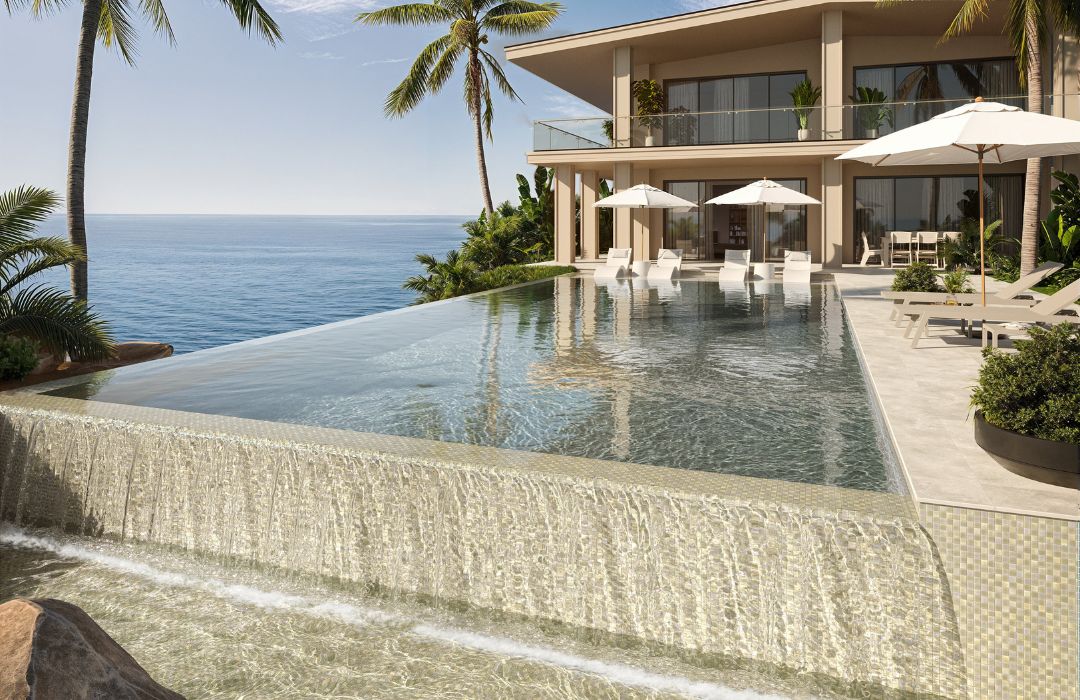 Luxury villa with an infinity pool overlooking the ocean, surrounded by palm trees.