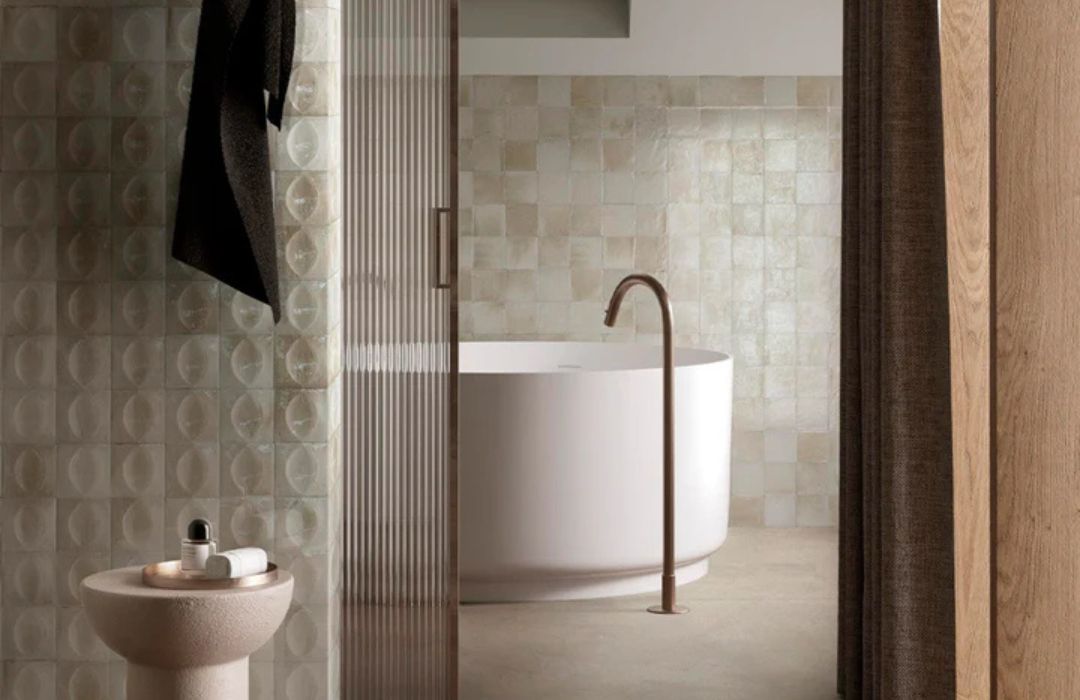 beige glossy bathroom tile with bathtub, towel and small table