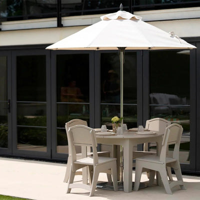 Outdoor dining set with table and chairs under a large umbrella in front of a building.